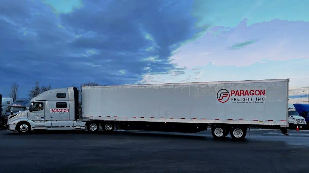 Paragon Freight Inc semi truck and 53ft dry van trailer in a yard at dusk — CDL-A carrier Burr Ridge IL
