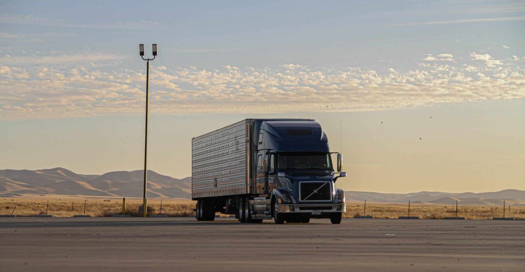 Semi truck driving on open highway at sunset — freight shipping and carrier selection