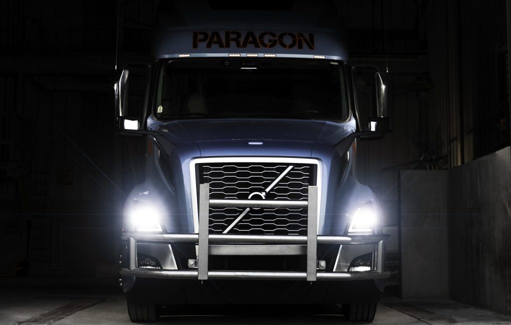 Paragon Freight Volvo semi-truck front view with headlights on at night