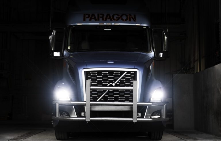 Paragon Freight Volvo semi-truck front view with headlights on at night